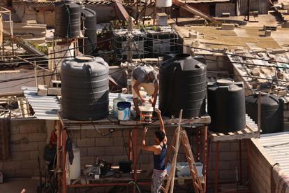 Dos hombres rellenan este vieners depósitos de agua de una vivienda en Rafah, al sur de la Franja. 