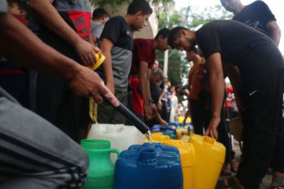 Palestinos llenan bidones de plástico en Rafah, en el sur de la franja de Gaza, en medio del ataqué israelí.