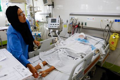 Una sanitaria atiende a un adolescente palestino ingresado en la Unidad de Cuidados Intensivos del hospital Nasser, de Gaza, este jueves. Los doctores de este centro han denunciado que solo pueden atener casos críticos debido a la escasez de combustible.
